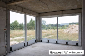 Nasze realizacje – Wiśniowski – Brama segmentowa UniTherm, okna PVC PRIMO 82, rolety zewnętrzne  Szukasz stolarki dla swojego domu, który ma być zarówno estetyczny, jak i energooszczędny? Zobacz naszą realizację, gdzie zastosowaliśmy kompleksowe rozwiązania Wiśniowski, gwarantujące funkcjonalność i niezawodność.  Lokalizacja realizacji: Drozdów  Okna PVC PRIMO 82 W tym projekcie postawiliśmy na okna PVC PRIMO 82, które wyróżniają się  świetnymi właściwościami izolacyjnymi. Na zewnątrz są w nowoczesnym kolorze - ciemnoszary jedwab, który idealnie pasuje do współczesnej architektury. Wewnątrz okna pozostały klasycznie białe (RAL 9016). Dodatkowo okna charakteryzuje bogate wyposażenie jak ciepłe ramki, zabezpieczenia antywłamaniowe, blokady antyprzeciągowe czy okucia z ukrytymi zawiasami.  Profil okien: PRIMO 82 Kolor zewnętrzny: Ciemnoszary jedwab Kolor wewnętrzny: Biały RAL 9016 Okucia: MACO MultiPower - zawiasy ukryte Wyposażenie: ciepła ramka, dwa zaczepy antywyważeniowe i najazd dolny, blokada antyprzeciągowa  Rolety Zewnętrzne Protecta P Dla zapewnienia prywatności i bezpieczeństwa zamontowaliśmy elektrycznie sterowane rolety zewnętrzne Protecta P. Ich pancerz PA-39 w kolorze szarego antracytu doskonale współgra z ramami okiennymi, tworząc spójną i elegancką całość. Rolety te to nie tylko świetna ochrona przed słońcem i hałasem, ale także dodatkowa bariera utrudniająca włamanie.  Rolety: Protecta P sterowane elektrycznie Pancerz: Pancerz PA-39 Kolor: Szary antracyt  Brama Segmentowa UniTherm Całość dopełnia nowoczesna brama segmentowa UniTherm w kolorze RAL 7016 (antracyt). Dzięki panelom typu G (bez przetłoczeń) brama wygląda minimalistycznie i bardzo elegancko, podkreślając nowoczesny styl budynku. Brama UniTherm to synonim najwyższej jakości, doskonałej izolacji termicznej i niezawodności, zapewniając łatwy i bezpieczny dostęp do garażu dzięki automatyce Wiśniowski SPARK 1100.  Brama: Segmentowa UniTherm Kolor: RAL 7016 Typ panela: G – bez przetłoczeń Automatyka: Wiśniowski SPARK 1100