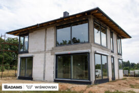 Nasze realizacje – Wiśniowski – Brama segmentowa UniTherm, okna PVC PRIMO 82, rolety zewnętrzne  Szukasz stolarki dla swojego domu, który ma być zarówno estetyczny, jak i energooszczędny? Zobacz naszą realizację, gdzie zastosowaliśmy kompleksowe rozwiązania Wiśniowski, gwarantujące funkcjonalność i niezawodność.  Lokalizacja realizacji: Drozdów  Okna PVC PRIMO 82 W tym projekcie postawiliśmy na okna PVC PRIMO 82, które wyróżniają się  świetnymi właściwościami izolacyjnymi. Na zewnątrz są w nowoczesnym kolorze - ciemnoszary jedwab, który idealnie pasuje do współczesnej architektury. Wewnątrz okna pozostały klasycznie białe (RAL 9016). Dodatkowo okna charakteryzuje bogate wyposażenie jak ciepłe ramki, zabezpieczenia antywłamaniowe, blokady antyprzeciągowe czy okucia z ukrytymi zawiasami.  Profil okien: PRIMO 82 Kolor zewnętrzny: Ciemnoszary jedwab Kolor wewnętrzny: Biały RAL 9016 Okucia: MACO MultiPower - zawiasy ukryte Wyposażenie: ciepła ramka, dwa zaczepy antywyważeniowe i najazd dolny, blokada antyprzeciągowa  Rolety Zewnętrzne Protecta P Dla zapewnienia prywatności i bezpieczeństwa zamontowaliśmy elektrycznie sterowane rolety zewnętrzne Protecta P. Ich pancerz PA-39 w kolorze szarego antracytu doskonale współgra z ramami okiennymi, tworząc spójną i elegancką całość. Rolety te to nie tylko świetna ochrona przed słońcem i hałasem, ale także dodatkowa bariera utrudniająca włamanie.  Rolety: Protecta P sterowane elektrycznie Pancerz: Pancerz PA-39 Kolor: Szary antracyt  Brama Segmentowa UniTherm Całość dopełnia nowoczesna brama segmentowa UniTherm w kolorze RAL 7016 (antracyt). Dzięki panelom typu G (bez przetłoczeń) brama wygląda minimalistycznie i bardzo elegancko, podkreślając nowoczesny styl budynku. Brama UniTherm to synonim najwyższej jakości, doskonałej izolacji termicznej i niezawodności, zapewniając łatwy i bezpieczny dostęp do garażu dzięki automatyce Wiśniowski SPARK 1100.  Brama: Segmentowa UniTherm Kolor: RAL 7016 Typ panela: G – bez przetłoczeń Automatyka: Wiśniowski SPARK 1100