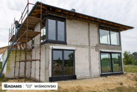 Nasze realizacje – Wiśniowski – Brama segmentowa UniTherm, okna PVC PRIMO 82, rolety zewnętrzne  Szukasz stolarki dla swojego domu, który ma być zarówno estetyczny, jak i energooszczędny? Zobacz naszą realizację, gdzie zastosowaliśmy kompleksowe rozwiązania Wiśniowski, gwarantujące funkcjonalność i niezawodność.  Lokalizacja realizacji: Drozdów  Okna PVC PRIMO 82 W tym projekcie postawiliśmy na okna PVC PRIMO 82, które wyróżniają się  świetnymi właściwościami izolacyjnymi. Na zewnątrz są w nowoczesnym kolorze - ciemnoszary jedwab, który idealnie pasuje do współczesnej architektury. Wewnątrz okna pozostały klasycznie białe (RAL 9016). Dodatkowo okna charakteryzuje bogate wyposażenie jak ciepłe ramki, zabezpieczenia antywłamaniowe, blokady antyprzeciągowe czy okucia z ukrytymi zawiasami.  Profil okien: PRIMO 82 Kolor zewnętrzny: Ciemnoszary jedwab Kolor wewnętrzny: Biały RAL 9016 Okucia: MACO MultiPower - zawiasy ukryte Wyposażenie: ciepła ramka, dwa zaczepy antywyważeniowe i najazd dolny, blokada antyprzeciągowa  Rolety Zewnętrzne Protecta P Dla zapewnienia prywatności i bezpieczeństwa zamontowaliśmy elektrycznie sterowane rolety zewnętrzne Protecta P. Ich pancerz PA-39 w kolorze szarego antracytu doskonale współgra z ramami okiennymi, tworząc spójną i elegancką całość. Rolety te to nie tylko świetna ochrona przed słońcem i hałasem, ale także dodatkowa bariera utrudniająca włamanie.  Rolety: Protecta P sterowane elektrycznie Pancerz: Pancerz PA-39 Kolor: Szary antracyt  Brama Segmentowa UniTherm Całość dopełnia nowoczesna brama segmentowa UniTherm w kolorze RAL 7016 (antracyt). Dzięki panelom typu G (bez przetłoczeń) brama wygląda minimalistycznie i bardzo elegancko, podkreślając nowoczesny styl budynku. Brama UniTherm to synonim najwyższej jakości, doskonałej izolacji termicznej i niezawodności, zapewniając łatwy i bezpieczny dostęp do garażu dzięki automatyce Wiśniowski SPARK 1100.  Brama: Segmentowa UniTherm Kolor: RAL 7016 Typ panela: G – bez przetłoczeń Automatyka: Wiśniowski SPARK 1100