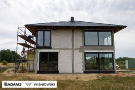Nasze realizacje – Wiśniowski – Brama segmentowa UniTherm, okna PVC PRIMO 82, rolety zewnętrzne  Szukasz stolarki dla swojego domu, który ma być zarówno estetyczny, jak i energooszczędny? Zobacz naszą realizację, gdzie zastosowaliśmy kompleksowe rozwiązania Wiśniowski, gwarantujące funkcjonalność i niezawodność.  Lokalizacja realizacji: Drozdów  Okna PVC PRIMO 82 W tym projekcie postawiliśmy na okna PVC PRIMO 82, które wyróżniają się  świetnymi właściwościami izolacyjnymi. Na zewnątrz są w nowoczesnym kolorze - ciemnoszary jedwab, który idealnie pasuje do współczesnej architektury. Wewnątrz okna pozostały klasycznie białe (RAL 9016). Dodatkowo okna charakteryzuje bogate wyposażenie jak ciepłe ramki, zabezpieczenia antywłamaniowe, blokady antyprzeciągowe czy okucia z ukrytymi zawiasami.  Profil okien: PRIMO 82 Kolor zewnętrzny: Ciemnoszary jedwab Kolor wewnętrzny: Biały RAL 9016 Okucia: MACO MultiPower - zawiasy ukryte Wyposażenie: ciepła ramka, dwa zaczepy antywyważeniowe i najazd dolny, blokada antyprzeciągowa  Rolety Zewnętrzne Protecta P Dla zapewnienia prywatności i bezpieczeństwa zamontowaliśmy elektrycznie sterowane rolety zewnętrzne Protecta P. Ich pancerz PA-39 w kolorze szarego antracytu doskonale współgra z ramami okiennymi, tworząc spójną i elegancką całość. Rolety te to nie tylko świetna ochrona przed słońcem i hałasem, ale także dodatkowa bariera utrudniająca włamanie.  Rolety: Protecta P sterowane elektrycznie Pancerz: Pancerz PA-39 Kolor: Szary antracyt  Brama Segmentowa UniTherm Całość dopełnia nowoczesna brama segmentowa UniTherm w kolorze RAL 7016 (antracyt). Dzięki panelom typu G (bez przetłoczeń) brama wygląda minimalistycznie i bardzo elegancko, podkreślając nowoczesny styl budynku. Brama UniTherm to synonim najwyższej jakości, doskonałej izolacji termicznej i niezawodności, zapewniając łatwy i bezpieczny dostęp do garażu dzięki automatyce Wiśniowski SPARK 1100.  Brama: Segmentowa UniTherm Kolor: RAL 7016 Typ panela: G – bez przetłoczeń Automatyka: Wiśniowski SPARK 1100